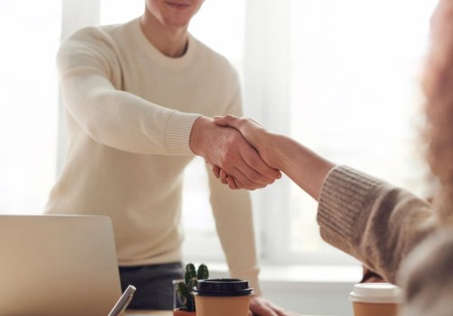 Dos personas dándose la mano en una reunión de negocios